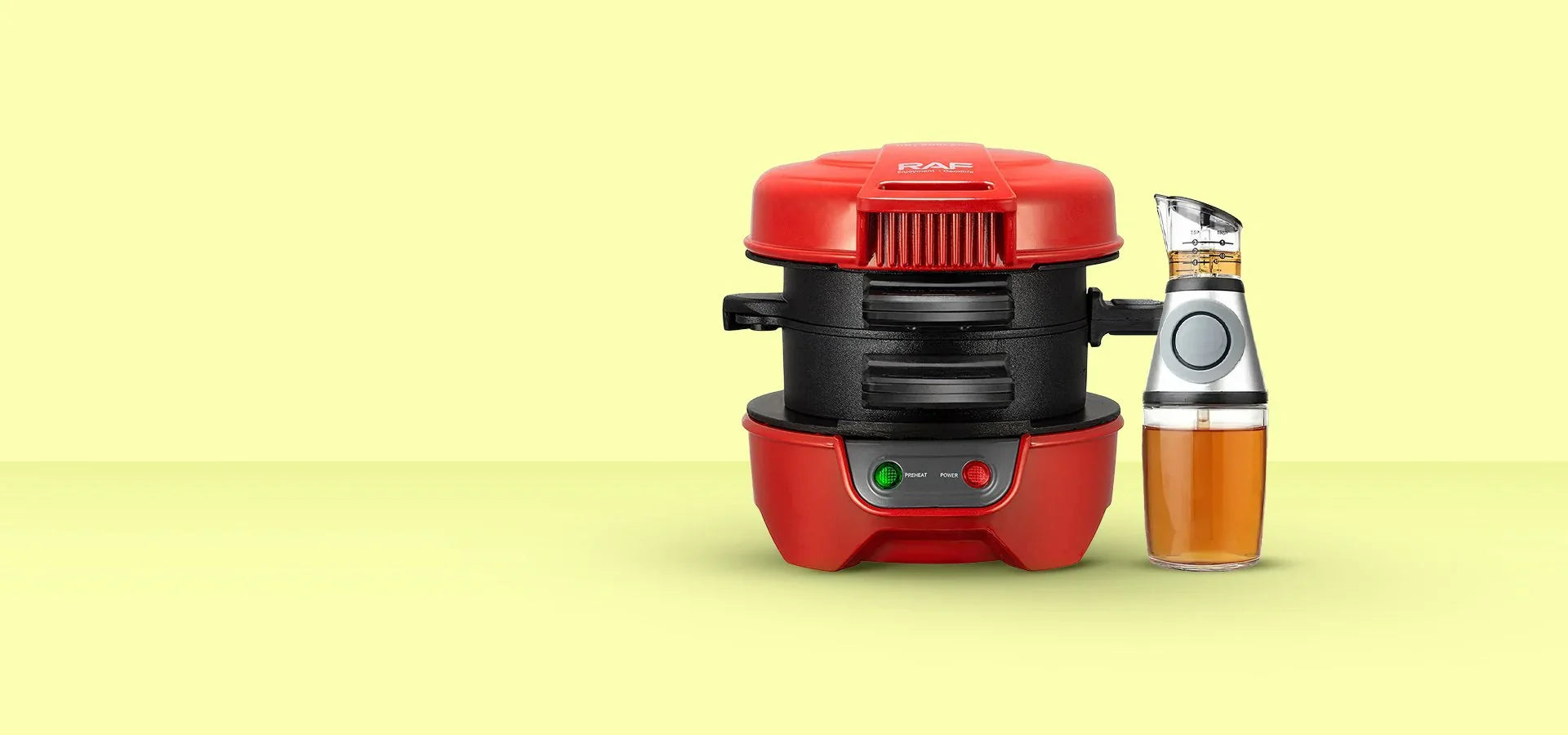 Електрически уред за сандвичи с червен цвят и дозатор за олио, изолирано на светло жълт фон