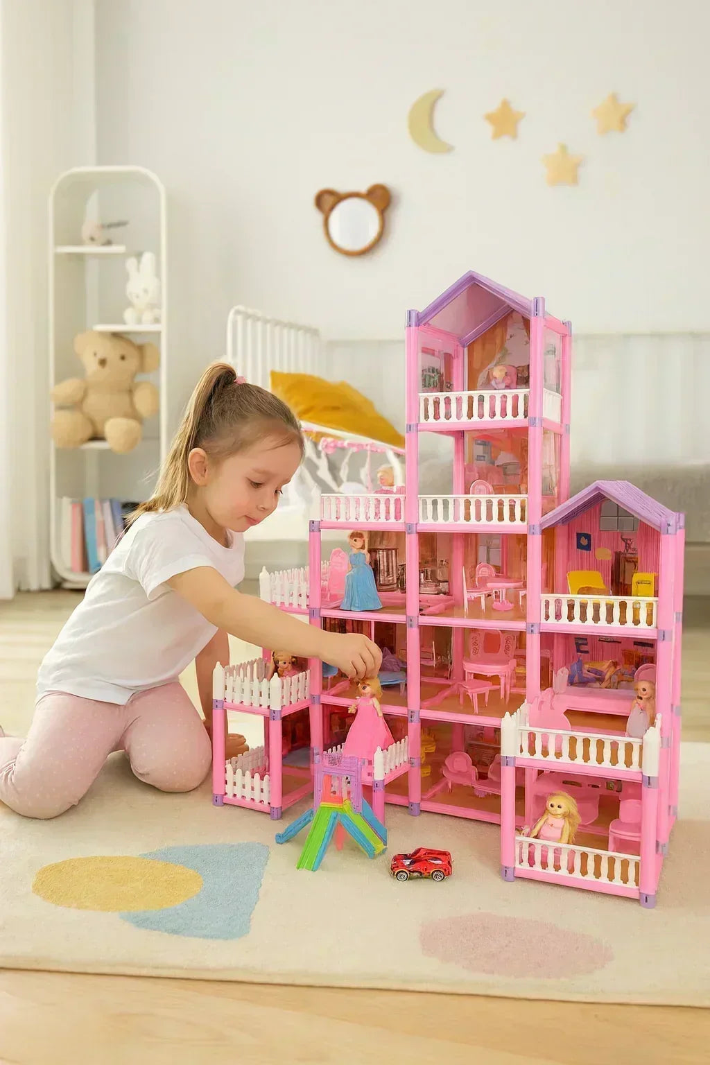 Момиченце играе с розова къща за кукли с мебели и фигурки, подходяща за детска стая.